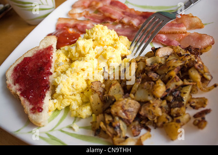 Una colazione completa con uova strapazzate bacon patate e toast. Foto Stock