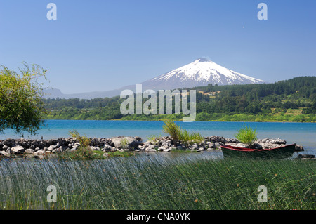 Il Cile, Los Lagos regione, provincia Araucania, Villarica, e reed barca sul Lago Villarrica con il Vulcano Villarrica in Foto Stock