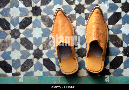 Una coppia di Marocchino tradizionale pantofola-scarpe (babouches) contro il mosaico tradizionale tilework (zellij) in Marrakech, Marocco Foto Stock
