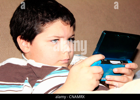 Un bambino o un bambino utilizzando un dispositivo elettronico o di un gioco o di Nintendo o il video gioco Foto Stock