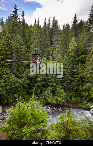 Gli amanti della mountain bike in sella alla mano tram oltre il vincitore Creek vicino a Girdwood centromeridionale, Alaska, estate Foto Stock