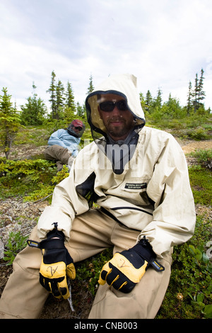 Due pescatori indossare le zanzariere e bug camicie mentre prendendo una pausa lungo il fiume Koktuli, Bristol Bay Area, Alaska Foto Stock