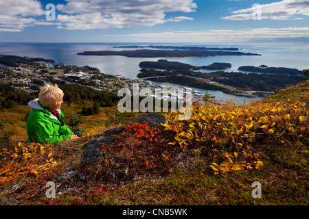 Donna matura si rilassa e gode di una vista del centro della città di Kodiak sul pilastro montagna, isola di Kodiak, Southwest Alaska, Autunno Foto Stock