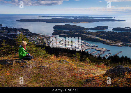 Donna matura si rilassa e gode di una vista del centro della città di Kodiak sul pilastro montagna, isola di Kodiak, Southwest Alaska, Autunno Foto Stock