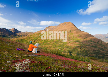 Donna matura escursioni e gode di paesaggi con cane sul vecchio Womens Mountain, Kodiak, Southwest Alaska, Autunno Foto Stock