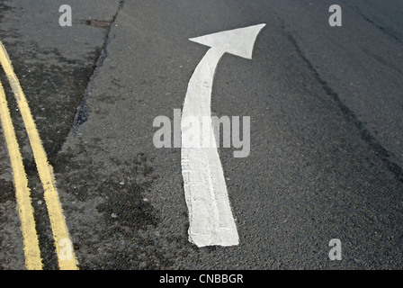 british road marking in form of right curving arrow, with double yellow lines to left Foto Stock