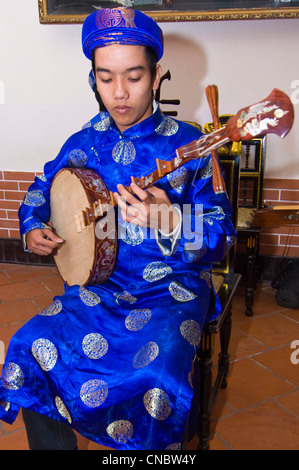 Verticale di vista ravvicinata della tradizionale vietnamita musicista che gioca il dan nguyet o Luna Piena liuto chitarra in costume. Foto Stock