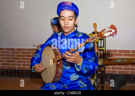 Orizzontale di vista ravvicinata della tradizionale vietnamita musicista che gioca il dan nguyet o Luna Piena liuto chitarra in costume. Foto Stock