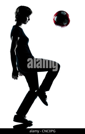 Un caucasian adolescente silhouette boy juggling soccer football per tutta la lunghezza in studio di ritagliare isolati su sfondo bianco Foto Stock