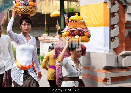 Donna con cesto sulla testa di qui a piedi Tirta Empul Temple a donare offerte per le bevande spiritose Foto Stock