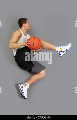 Giocatore di basket eseguendo un difficile salto con una sfera Foto Stock