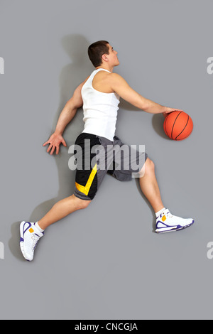 Guy dribblare la palla pronto a buttare nel cestino di vista di cui sopra Foto Stock