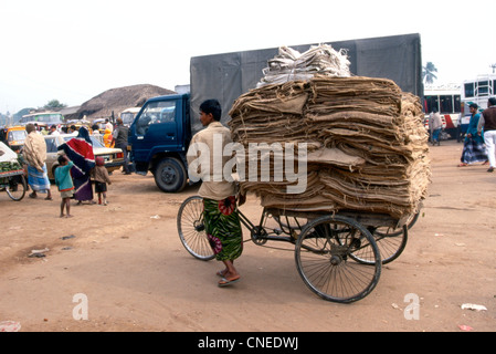La vita di strada dominato da Rickshaw qui un uomo il trasporto di iuta Foto Stock
