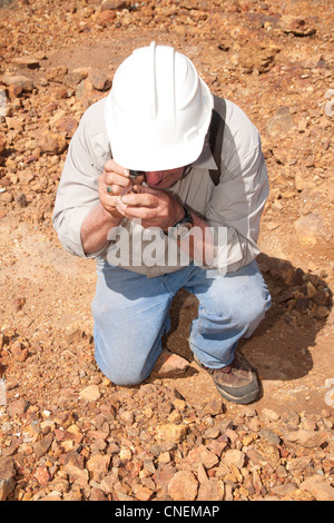 Senior Exploration Geologist analizzando campioni di roccia con una lente a mano presso la storica Macalder miniera di rame, Kenya occidentale Foto Stock