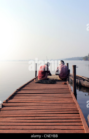 I pescatori seduti su una piattaforma di legno con la cattura di pesce in early moning vicino villaggio cherai a Kochi, Kerala, India Foto Stock