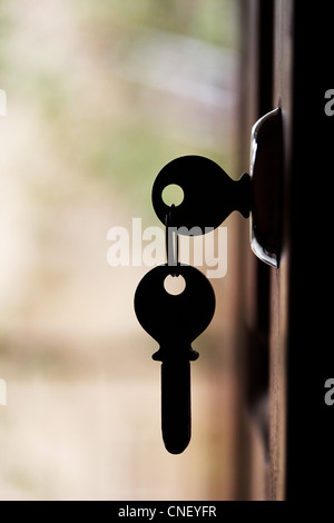 Silhouette della chiave della porta appeso sulla porta aperta con sfondo sfocato Foto Stock