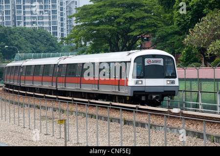 Un treno della metropolitana azionato da SMRT si avvicina ad una stazione su una sezione aperta della linea Foto Stock