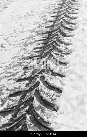 Close up del trattore via a sinistra dietro in snow bound road cancellata dalla neve aratro Foto Stock