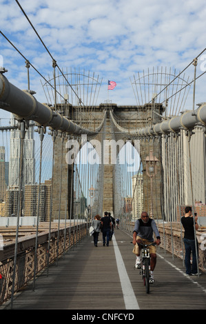 Blue sky ritratto cavi di sospensione tower, bandiera americana, pedonale, Asiatico-americano ciclista, il Ponte di Brooklyn, New York Foto Stock