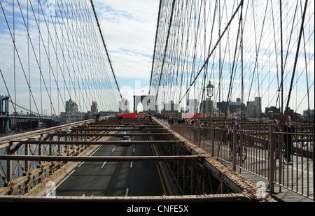 Vista, verso lo skyline di Brooklyn, persone ciclisti su strada pedonale sopra a traliccio metallico ponte stradale, Ponte di Brooklyn a New York Foto Stock