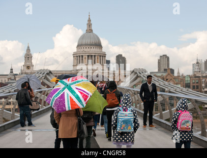 Millennium Bridge City di Londra dopo una molla leggera doccia i turisti amano camminare verso la Cattedrale di St Paul e sotto gli ombrelloni Foto Stock