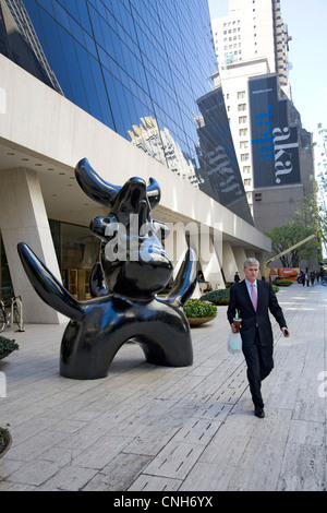 L'uomo cammina da Joan Miro "oonbird' scultura (1966), che si trova sulla piazza del Solow edificio sulla 58th Street in NYC Foto Stock