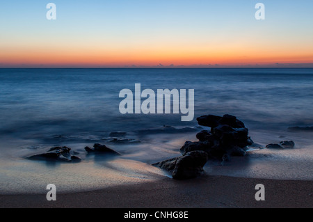 Un sunrise immagine presa a Washington oaks giardini del parco statale in Palm Coast, fl. Questo è sul lato oceano del parco. la roccia fuori-mozzare in questa immagine è composta da coquina rock, che è una combinazione di conchiglie di mare e sabbia legati insieme con calcite. Questa pietra è stata utilizzata per la costruzione nella zona per secoli. washington oaks gardens state park è situato a sud di st. Agostino nella città di palm coast. L'albergo era una volta di proprietà di un parente lontano di George Washington. I giardini, situato tra la costa e il fiume Mantanzas sono stati stabiliti da louise e owen Foto Stock