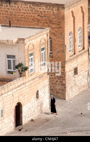 Una donna cristiana siriaca che si trova fuori dalla sua casa nella città vecchia di Midyat, nella regione orientale dell'Anatolia, nella Turchia sudorientale. Foto Stock