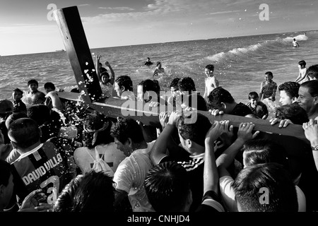 Seguaci cattolici portano la croce di legno in mare durante l annuale Settimana santa rituale di santa elena, Ecuador. Foto Stock