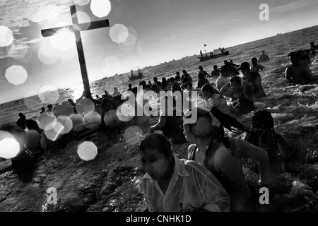 Seguaci cattolica bagno la croce di legno in mare durante l annuale Settimana santa rituale di santa elena, Ecuador. Foto Stock