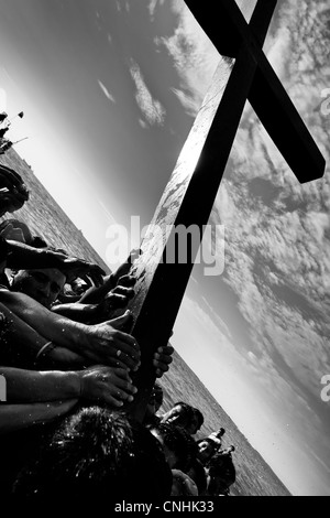 Seguaci cattolici portano la croce di legno in mare durante l annuale Settimana santa rituale di santa elena, Ecuador. Foto Stock