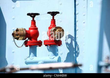 Rosso rubinetto industriale ruota su sfondo blu, nessuno Foto Stock