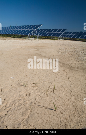 Massa secca accanto alle righe di pannelli solari in un campo Foto Stock