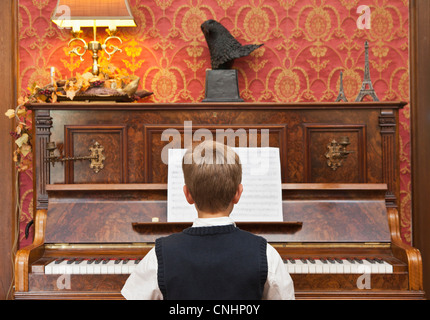 Un ragazzo praticare su un pianoforte verticale Foto Stock