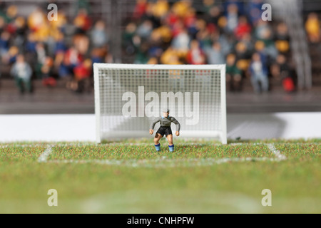 Una miniatura soccer goalie figurina custodendo l'obiettivo post Foto Stock