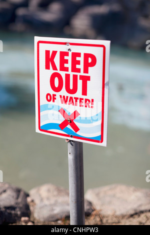 A tenere fuori del segno d'acqua postato su una spiaggia rocciosa Foto Stock