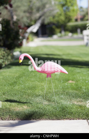 Un fenicottero rosa di plastica incollato in un prato, close-up Foto Stock