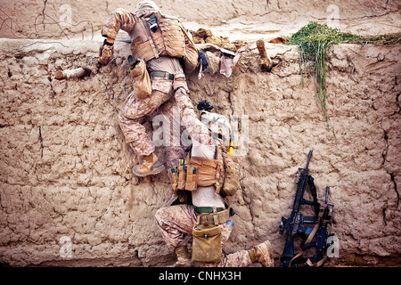 Marines americani salire una parete a prendere posizione su un tetto durante una ricerca di un villaggio composto 14 aprile 2012 nella provincia di Helmand, Afghanistan. Foto Stock