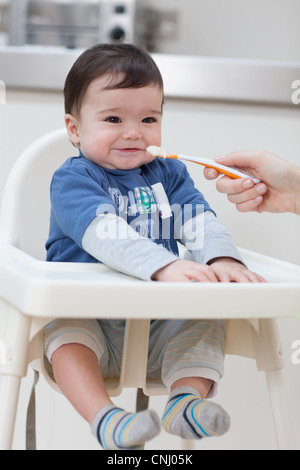 Alimentazione adulto bambino in sedia alta Foto Stock