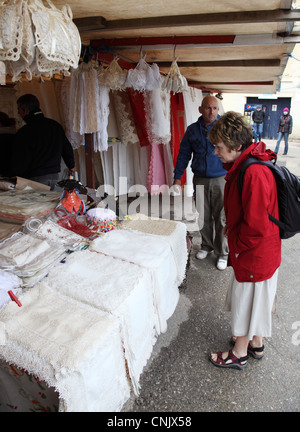 Donna matura guardando bancarella vendendo pizzi mercato aperto, Marsaxlokk, Malta, Europa Foto Stock