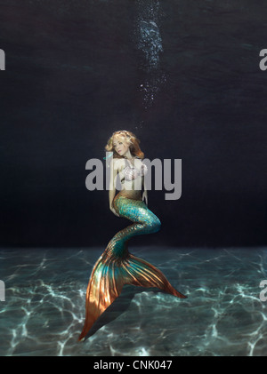 Mermaid underwater galleggiante sopra il fondo sabbioso Foto Stock