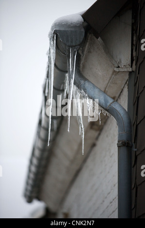 Ghiaccioli formata intorno l'acqua congelata in grondaie su proprietà immobiliari di tipo residenziale Foto Stock