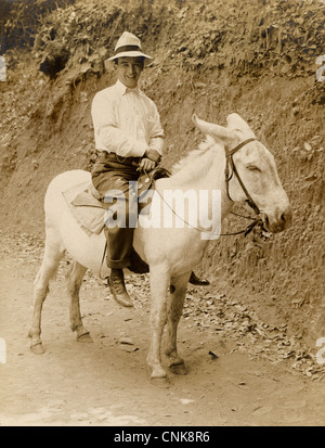 Uomo felice cavalcando un asinello bianco Foto Stock