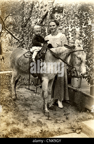 Piuttosto giovane madre con figlio giovane asino di equitazione Foto Stock