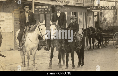 Due uomini & Boy a cavallo in città western Foto Stock