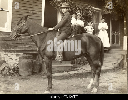 Ragazzo incerto sul cavallo guardato dalla sua famiglia Foto Stock