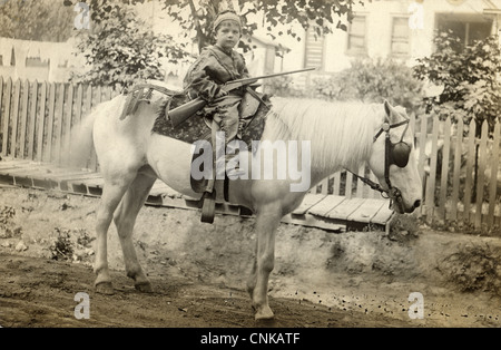 Armati ragazzo piccolo capo indiano in sella ad un cavallo bianco Foto Stock