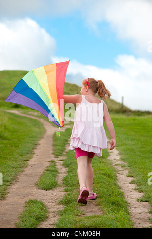 Un dai capelli rossi ragazza con un arcobaleno kite on Maiden Castle, Dorchester Dorset, Foto Stock