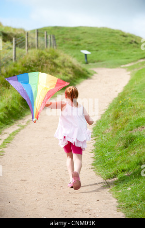 Un dai capelli rossi ragazza con un arcobaleno kite on Maiden Castle, Dorchester Dorset, Foto Stock