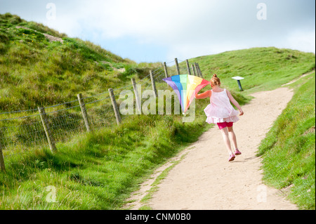 Un dai capelli rossi ragazza con un arcobaleno kite on Maiden Castle, Dorchester Dorset, Foto Stock